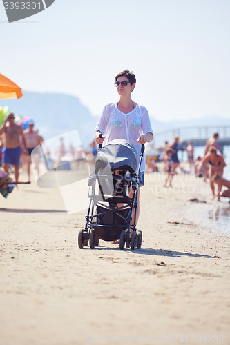 Image of mother walking on beach and push baby carriage