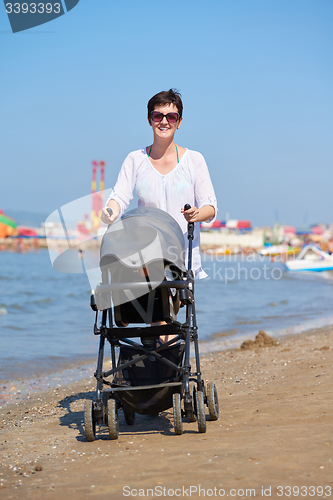 Image of mother walking on beach and push baby carriage