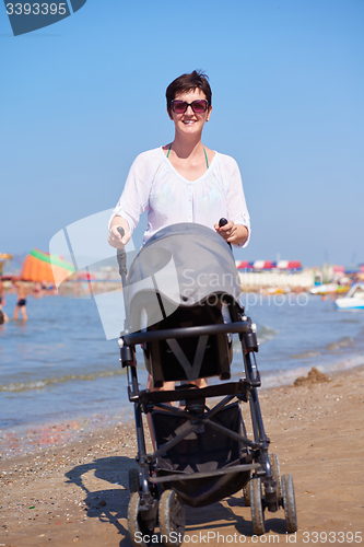 Image of mother walking on beach and push baby carriage