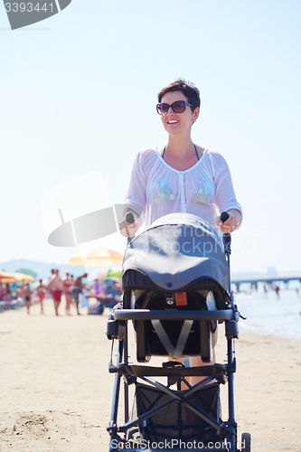 Image of mother walking on beach and push baby carriage