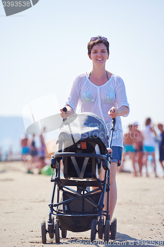 Image of mother walking on beach and push baby carriage