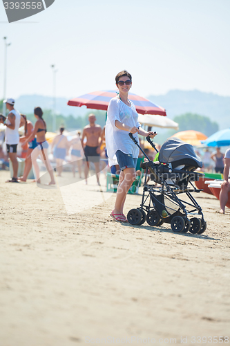 Image of mother walking on beach and push baby carriage
