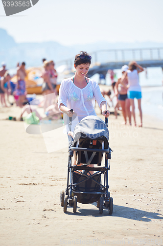 Image of mother walking on beach and push baby carriage