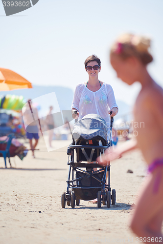 Image of mother walking on beach and push baby carriage