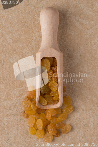 Image of Wooden scoop with golden raisins