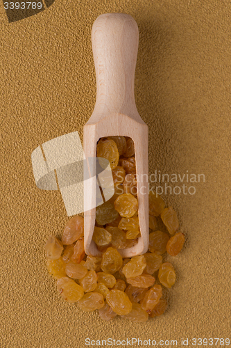 Image of Wooden scoop with golden raisins