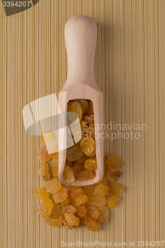 Image of Wooden scoop with golden raisins