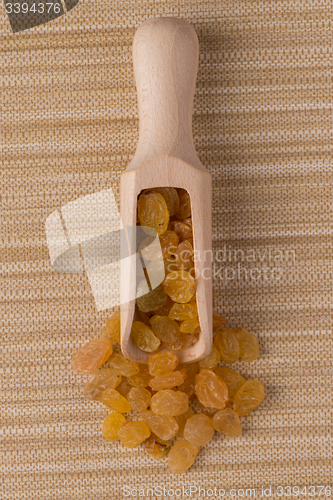 Image of Wooden scoop with golden raisins