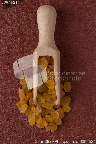 Image of Wooden scoop with golden raisins