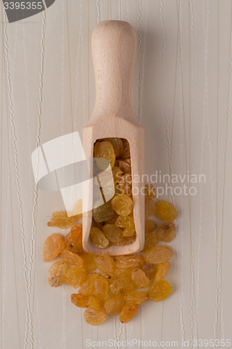 Image of Wooden scoop with golden raisins