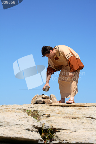 Image of Man picking up rock or making rock pile.