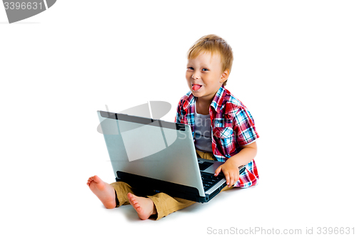 Image of little boy with a laptop sitting on the floor