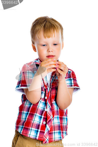 Image of little boy stands and examines small toy