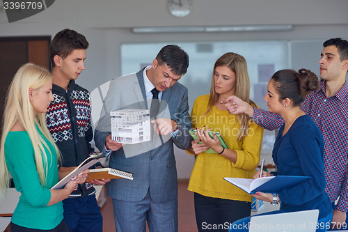 Image of group of students working with teacher on  house model