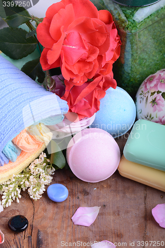 Image of Towels with lily, aroma oil,  candles and sea salt on wooden plate