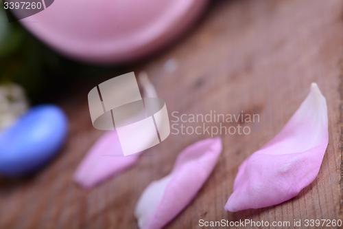 Image of sea salt, spa stones and flower petals on wooden table, closeup