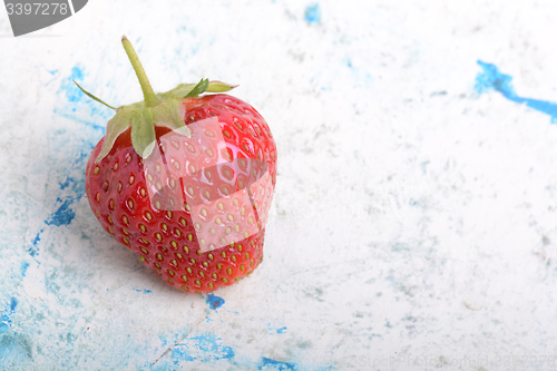 Image of Close-up detail of a fresh red strawberry with leaves