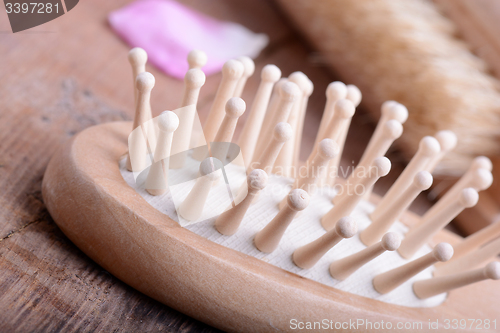 Image of hair brush, rose flower petals, comb on wooden plate. close up