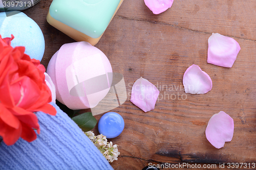 Image of sea salt, spa stones, towels, soap and flower petals on wooden table, closeup