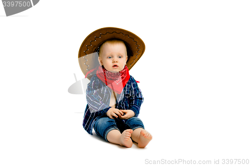 Image of boy in a cowboy hat sitting on a white floor