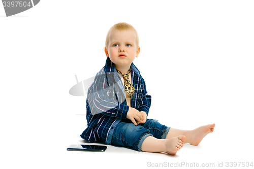 Image of boy in a tie sitting on a white floor