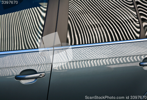 Image of Car and stripes, car parked in front of a building with striped 