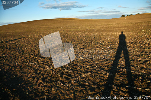 Image of Man shade on a field in Denmark in autumn with a blue sky