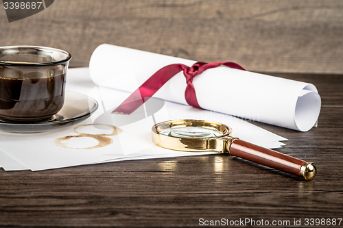 Image of Coffee cup, paper sheets and detective magnifying glass