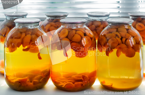 Image of Home canning: large glass cylinders with apricot compote.