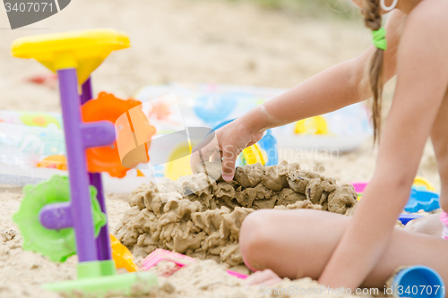 Image of The girl builds a sand castle wall