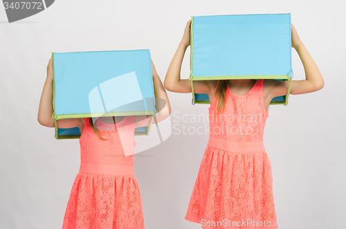 Image of Two girls with boxes on their heads