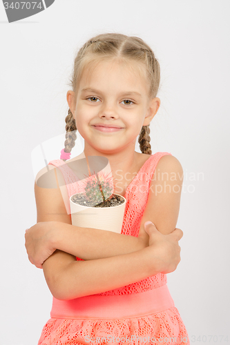 Image of Happy little girl hug pot of cactus