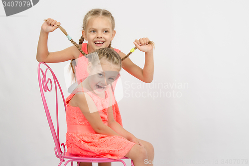 Image of Girl having fun with pigtails sister