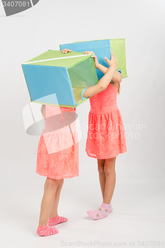 Image of Two girls play about putting on a head box