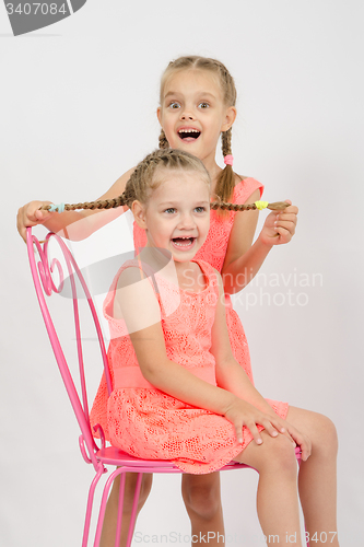 Image of Girl having fun holding the other girl braids hair