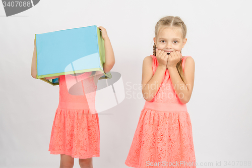 Image of Girl scared sister wearing a box on his head