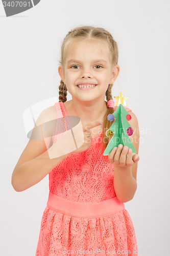 Image of Happy girl showing on the Christmas tree made of cardboard