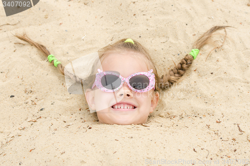 Image of Five-year girl fell asleep on his head in the sand