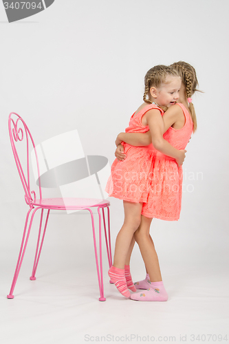 Image of Girl trying to sit on a chair his sister