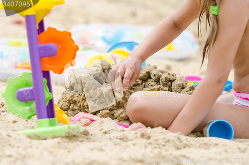 Image of The girl builds a sand castle