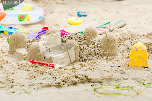 Image of Sand castle circle and toys on the river bank