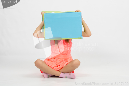 Image of Girl sitting the floor with a box on his head