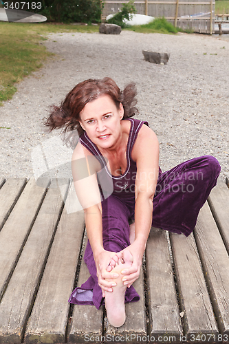 Image of Young woman doing stretching exercises outdoors