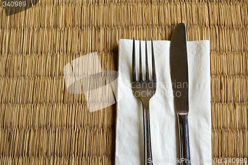 Image of Fork and knife on a dried grass mat

