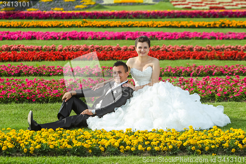 Image of Bride and groom posing on lawn with flowers