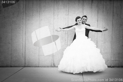 Image of Bride and groom spreading arms bw