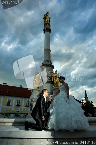 Image of Bride and groom posing in front of city fountain