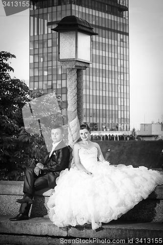 Image of Newlyweds sitting next to street lamp bw