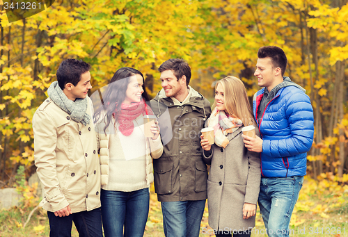 Image of group of smiling friend with coffee cups in park