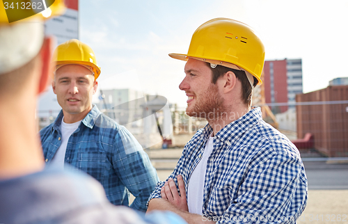 Image of group of smiling builders in hardhats outdoors